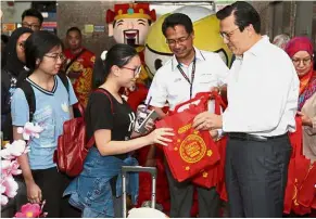  ??  ?? Spreading cheer: Liow giving out goodie bags to KTM passengers heading back to their hometowns to celebrate Chinese New Year. Looking on is KTM Berhad CEO Mohd Rani Hisham Samsudin (next to Liow).