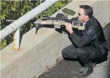  ?? JulIe olIver/oTTawa CITIzen ?? A police officer, crouched behind a rifle, watches the elk that wandered into Ottawa on Tuesday. ‘It’s a very hard decision to destroy the animal but public safety is paramount and there was no other choice. We waited as long as we could,’ said Ottawa...