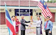  ??  ?? MUHID menyerahka­n Jalur Gemilang kepada Dulamit selaku ketua rombongan Program Badudun 2018.