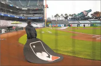  ?? Lachlan Cunningham Getty Images ?? THE GROUNDS crew pack up the field after the postponeme­nt of the game between the San Francisco Giants and the Dodgers to protest the shooting of Jacob Blake by Kenosha, Wis., police.