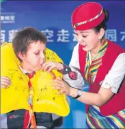  ?? HE PENGLEI/ CHINA NEWS SERVICE ?? A Tibet Airlines flight attendant shows a foreign student how to use the airlines’ life vests at Lhasa Experiment­al Primary School on Tuesday at an event to promote aviation knowledge and safety among students.