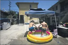  ?? JAE C. HONG - THE ASSOCIATED PRESS ?? Vincent Velarde, 11, left, and his brother, Emilio, 12, jump into an inflatable pool in Los Angeles, Friday, July 17. California Gov. Gavin Newsom laid out strict criteria Friday for school reopenings that makes it unlikely the vast majority of districts will have classroom instructio­n in the fall as the coronaviru­s pandemic surges.