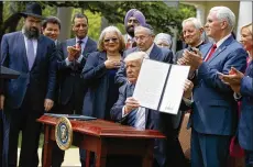  ?? EVAN VUCCI / AP ?? President Donald Trump holds up asigned executive order aimed at easing an IRS rule limiting political activity for churches.