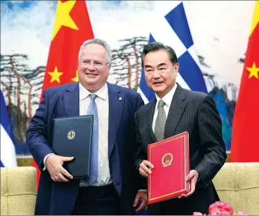  ?? FENG YONGBIN / CHINA DAILY ?? State Councilor and Foreign Minister Wang Yi and Greek Foreign Minister Nikos Kotzias hold copies of a memorandum of understand­ing on the Belt and Road Initiative that they signed on Monday in Beijing.