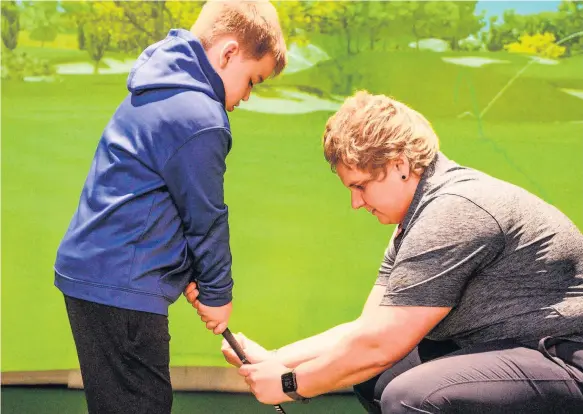  ??  ?? Natasha Gobey helps a burgeoning young golf talent get into the swing of things