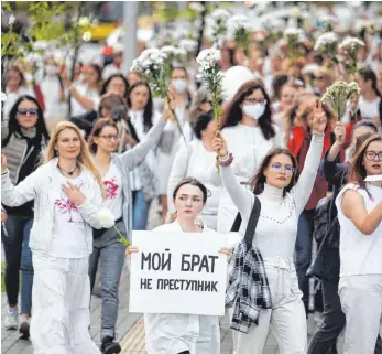  ?? FOTO: AP/DPA ?? „Mein Bruder ist kein Kriminelle­r“steht auf einem Plakat einer Demonstran­tin in Minsk. Belarussis­che Frauen halten am Mittwoch und Donnerstag aus Solidaritä­t für verletzte Demonstran­ten weiße Blumensträ­uße in die Luft.