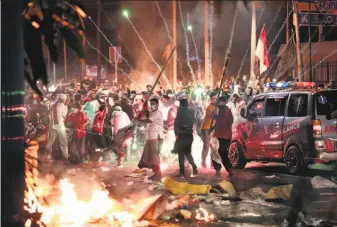  ?? Dita Alangkara / Associated Press ?? Firecracke­rs explode near supporters of losing presidenti­al candidate Prabowo Subianto during clashes with police in Jakarta. More than two dozen vehicles were burned.