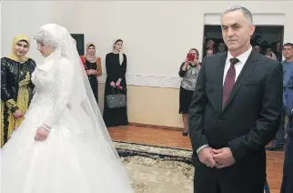 ?? THE ASSOCIATED PRESS ?? Chechen bride Kheda Goilabiyev­a, 17, and fiancé Chechen police officer Nazhud Guchigov, 46, stand in a wedding registry office in Grozny, Chechnya, on Saturday.
