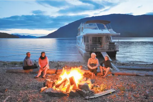  ?? Margo Pfeiff / Special to The Chronicle ?? With the houseboat securely anchored, the adventurer­s light a cheery bonfire on a Shuswap Lake beach. With a lavishly equipped kitchen and a barbecue, and gourmet supplies readily available, there’s no need for the travelers to actually cook on the...