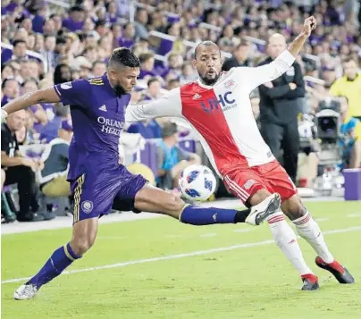  ?? JOHN RAOUX/ASSOCIATED PRESS ?? Orlando City's Amro Tarek, left, tries to clear the ball from New England’s Teal Bunbury on Saturday. Tarek scored the Lions’ second goal.