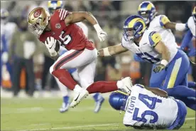 ?? AP photo ?? Niners running back Eli Mitchell runs against the Rams’ Leonard Floyd and Troy Reeder during the first half of San Francisco’s 31-10 victory over Los Angeles on Monday.