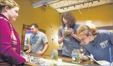  ?? Erin Hull Coloradoan ?? CUSTOMERS CHECK out marijuana at Organic Alternativ­es in Fort Collins, Colo. Two pot users in the state have sued LivWell Inc., which operates one of the largest grow houses in the world.