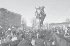  ??  ?? A police officer tries to get protesters down from a lamp post in downtown Moscow, Russia, on Sunday.