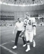  ?? Denver Post file ?? Broncos coach Red Miller walks off the field in 1977 with left tackle Andy Maurer.