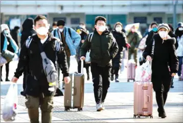  ?? PIC/PTI ?? Travelers wear face masks as they walk outside the Beijing Railway Station