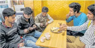  ??  ?? Students browse internet on their mobile phones as they sit inside a restaurant in Srinagar on Wednesday.