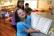  ?? CHARLES KRUPA — THE ASSOCIATED PRESS ?? Lily Osgood, 7, who has Down syndrome, shows off her completed work with her mother, Jennifer, and brother, Noah, 12, July 20at their home in Fairfax, Vt. For some families, the switch to homeschool­ing was influenced by their children’s special needs. Having observed Lily’s progress with reading and arithmetic while at home during the pandemic, Jennifer is convinced homeschool­ing is the best option for her going forward.