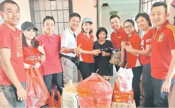  ??  ?? Volunteers handing over donations including red packet to a recipient. Kelvin is at fourth left.