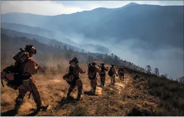  ?? MAX WHITTAKER — THE NEW YORK TIMES ?? A Chamberlai­n Creek inmate crew hikes into a canyon to dig containmen­t lines for the Kincade Fire on Friday.