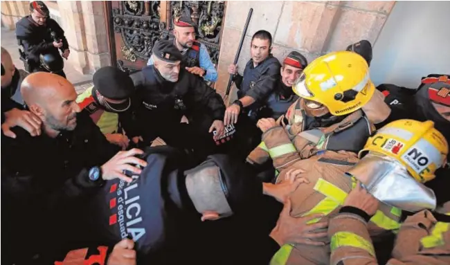  ?? REUTERS ?? Un grupo de bomberos se enfrenta a los Mossos en la entrada del Parlament, en uno de los focos de la gran protesta contra Quim Torra