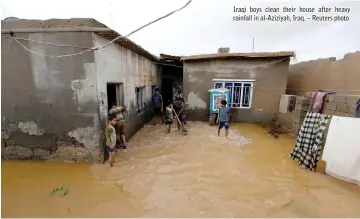  ??  ?? Iraqi boys clean their house after heavy rainfall in al-Aziziyah, Iraq. – Reuters photo