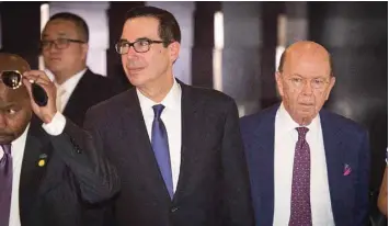  ??  ?? US Treasury Secretary Steven Mnuchin (L) and US Commerce Secretary Wilbur Ross (R) walk through a hotel lobby as they head to the Diaoyutai State Guest House to meet Chinese officials for ongoing trade talks in Beijing. — AFP