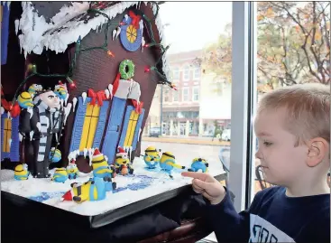  ?? Kristina Wilder / Rome News-Tribune ?? Joseph Burnham, 3, of Rome, points out his favorite part of Honeymoon Bakery’s gingerbrea­d house, the Minion holding a puppy.