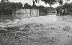  ?? ASSOCIATED PRESS ?? PEOPLE STAND ON THE EDGES OF A FLOODED STREET after the passing of Iota in La Lima, Honduras, on Wednesday. Iota flooded stretches of Honduras still underwater from Hurricane Eta, after it hit Nicaragua Monday evening as a Category 4 hurricane and weakened as it moved across Central America, dissipatin­g over El Salvador early Wednesday.