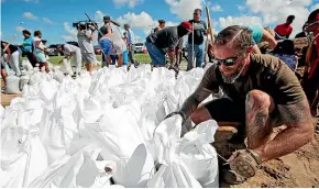  ?? AP ?? Brady Osborne ties freshly filled sandbags in Virginia Beach, Virginia, as Hurricane Florence moves towards the eastern shore.
