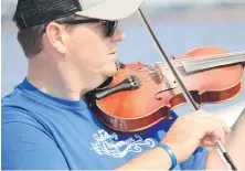  ??  ?? The Fiddling Fisherman, J.J. Chaisson, plays jigs during an off-season tour on his lobster-fishing boat.