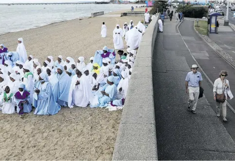  ?? Pictures: Reuters ?? MASS BAPTISM. People walk near the seafront as members of the Apostles of Muchinjikw­a Christian worship before a mass baptism on the beachfront on Southend-on-Sea in Britain.
