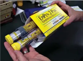  ?? Associated Press ?? In this July 8 file photo, a pharmacist holds a package of EpiPen epinephrin­e auto-injectors, a Mylan NV product, in Sacramento, Calif. Mylan said it will make available a generic version of its EpiPen, as criticism mounts over the price of its...