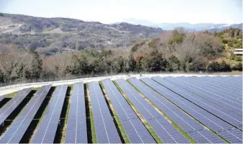  ?? — Reuters ?? Solar panels are seen at a solar power facility as snow covered Mount Fuji is pictured in Kanagawa prefecture, Japan.