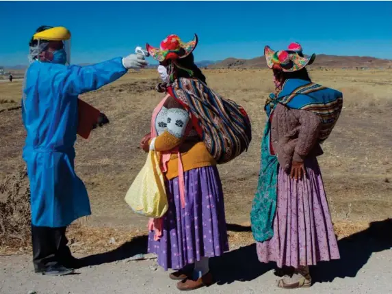  ?? (AFP) ?? A health worker checks the temperatur­e of two women heading to the weekly market in Coata, near Puno in southern Peru, close to the border with Bolivia