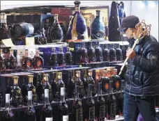  ?? WANG GANG / CHINA NEWS SERVICE PROVIDED TO CHINA DAILY ?? Left: A customer walks past an array of imported alcoholic products at a supermarke­t in Hangzhou, capital of Zhejiang province. Right: Consumers queue up for payments at a duty-free store in Beijing.