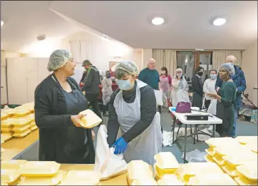  ??  ?? Andrew (right) talks to volunteer Diane Proctor (foreground left) as members of the Preston Windrush Covid Response team dish out West Indian meals at the Xaverian Sanctuary.