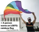  ?? Chip Somodevill­a ?? > A person waves an LGBTQ rainbow flag