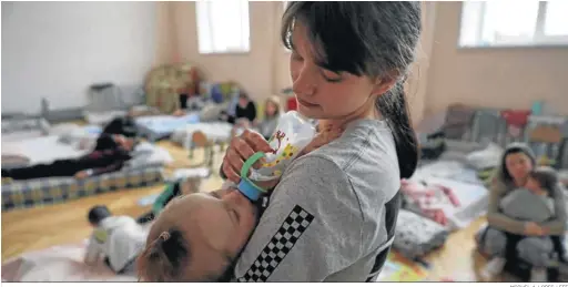  ?? MIGUEL A. LOPES / EFE ?? Una joven procedente de Kiev alimenta a su bebé en una guardería reconverti­da en refugio cerca de Leópolis.
