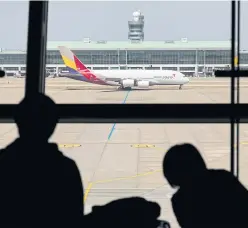  ?? BLOOMBERG ?? People look out of a window as an Airbus A380-841 aircraft operated by Asiana Airlines taxies on the tarmac at Incheon Internatio­nal Airport in this file photo.