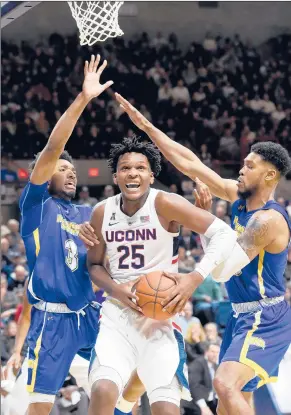  ??  ?? UConn forward Josh Carlton looks for room as he is double-teamed by Morehead State’s James Baker (3) and A.J. Hicks in the season opener.