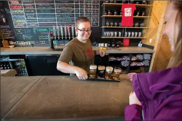  ?? NWA Democrat-Gazette/J.T. WAMPLER ?? Taptender Hannah Gilliam serves a sample flight of beers to a customer Sunday at New Province Brewing Co. in Rogers. A report from earlier this year ranked Northwest Arkansas 180th out of the 200 best metropolit­an areas for small business.