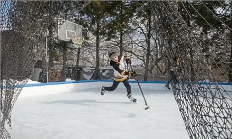  ?? Pam Panchak/Post-Gazette ?? Finn Tiernan, 11, takes a practice shot during a late-morning skating session on the backyard ice rink (after a morning of schoolwork) on Wednesday in Castle Shannon.