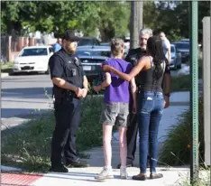  ??  ?? Deborah Golden (center) talks with Detroit police after she tried to render aid to a young girl who later died of her injuries in Detroit on Monday. MAx ortIz/detroIt neWS VIA AP