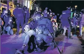  ?? ÀLEX GARCIA ?? Un policía detiene a una joven durante los disturbios de anoche