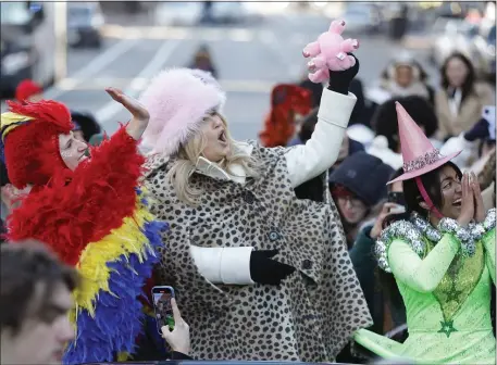  ?? PAUL CONNORS — BOSTON HERALD ?? Actor Jennifer Coolidge, center, the Hasty Pudding Woman of the Year, flanked by cast members Lyndsey Mumford, left, and Nikita Hair, right, waves a stuffed pig that was tossed down to her from a second-story window during a parade in her honor Saturday in Cambridge.