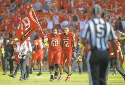  ?? PATRICK SEMANSKY/ASSOCIATED PRESS ?? Maryland offensive lineman Ellis McKennie celebrates the Terps’ win over Texas with teammate Taivon Jacobs as he waves a flag in remembranc­e of offensive lineman Jordan McNair, who died of heatstroke suffered during a team conditioni­ng test.