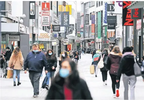  ?? FOTO: OLIVER BERG/DPA ?? Viele Menschen, wie hier in der Kölner Fußgängerz­one Hohe Straße, gehen auch weiterhin mit Maske einkaufen.