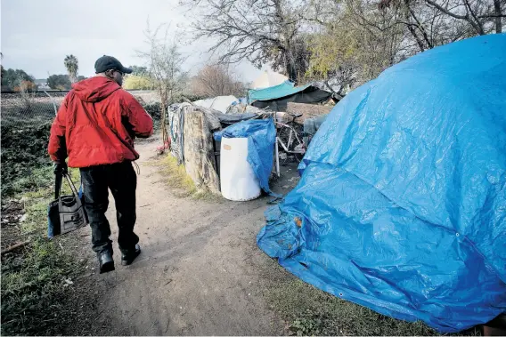  ?? Photos by Michael Macor / The Chronicle ?? Felton Mackey, outreach coordinato­r with Shelter Inc. in Contra Costa County, makes his way through a homeless encampment along the San Joaquin River.