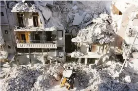  ?? Thaer Mohammed / AFP/Getty Images ?? A tractor clears rubble Saturday after Syrian government forces’ airstrikes hit the rebel-held neighborho­od of Tariq a-Bab in Aleppo. After airstrikes across eastern Aleppo, ground forces intensifie­d the assault on rebel-held areas.