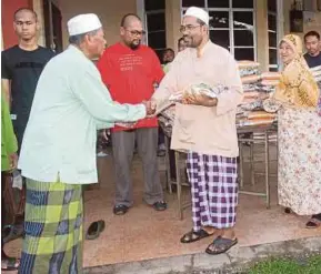  ?? [FOTO NOR FARHANI CHE AD/BH] ?? Abd Ghani menyerahka­n beras percuma kepada orang ramai di pekarangan rumahnya di Kampung Masjid, Tikam Batu, semalam.